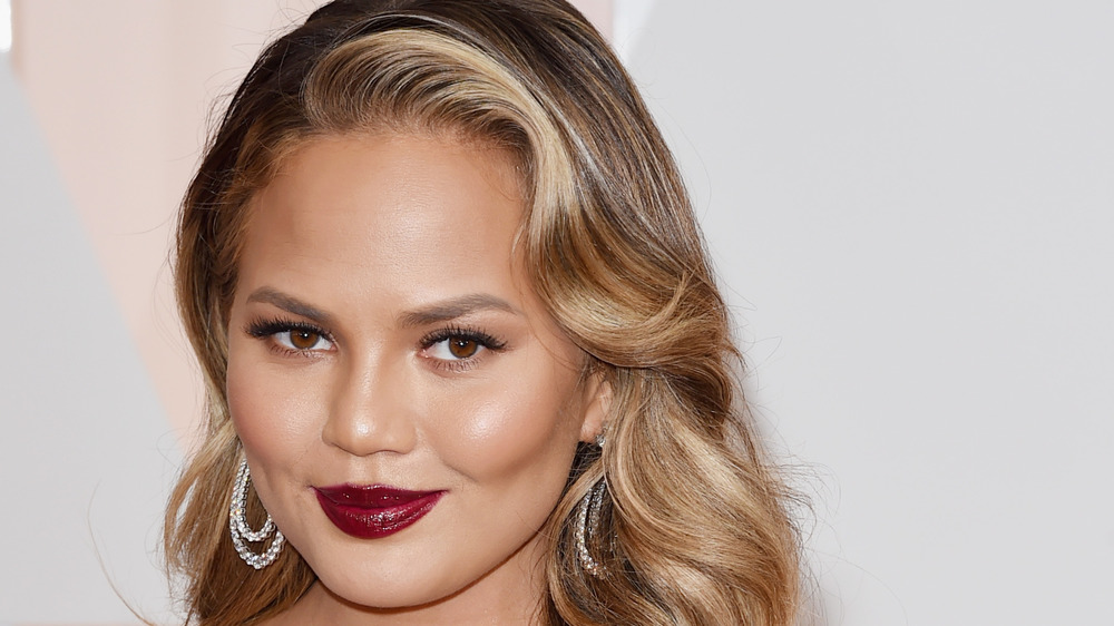 Chrissy Teigen smiling, red lipstick