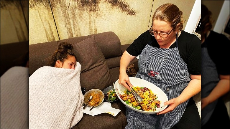Chrissy Teigen laying near Adeena Sussman