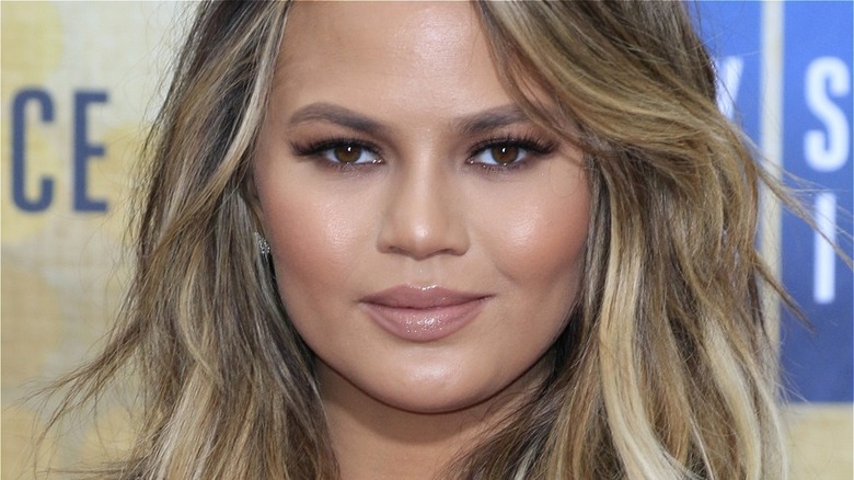 A close up of Chrissy Teigen with her hair down and blonde highlights