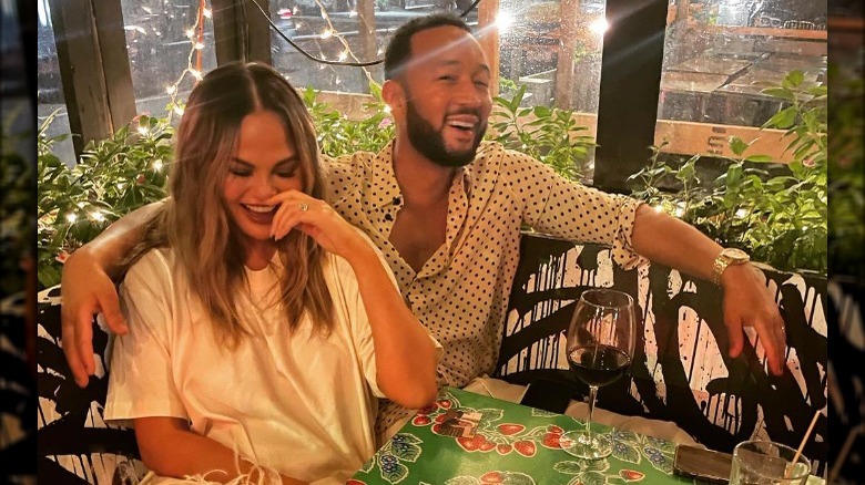 Chrissy Teigen and John Legend smiling at outdoor restaurant