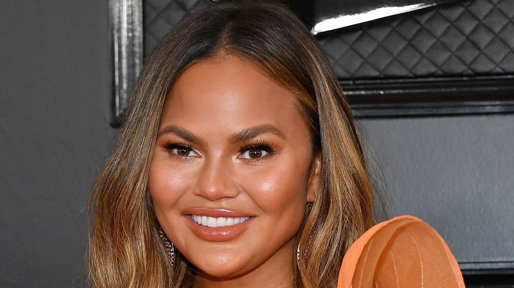 Chrissy Teigen wearing orange dress