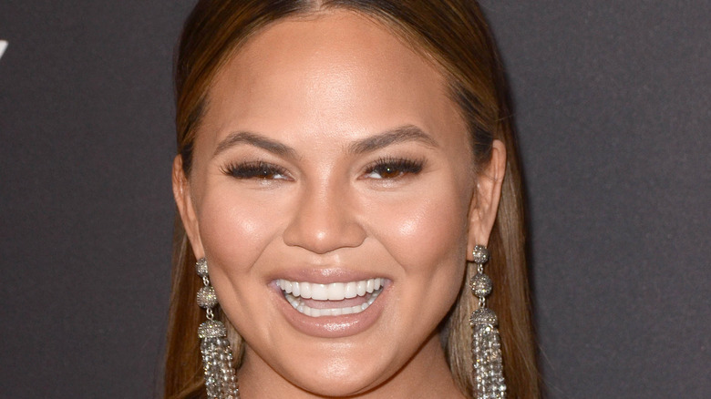 Chrissy Teigen in oversized earrings laughing