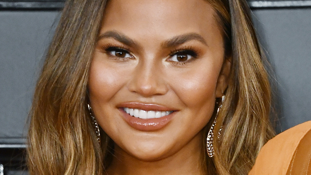 Chrissy Teigen wears bright orange dress