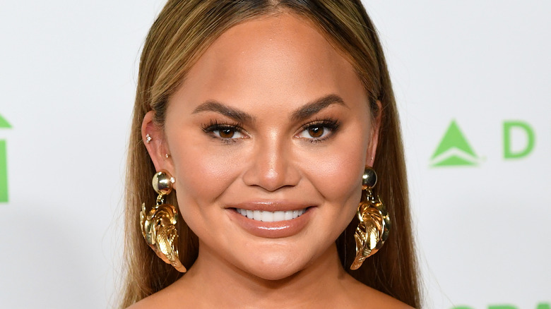 Chrissy Teigen wearing orange dress