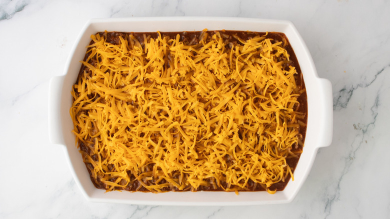 Chili dip topped with cheddar cheese in casserole dish