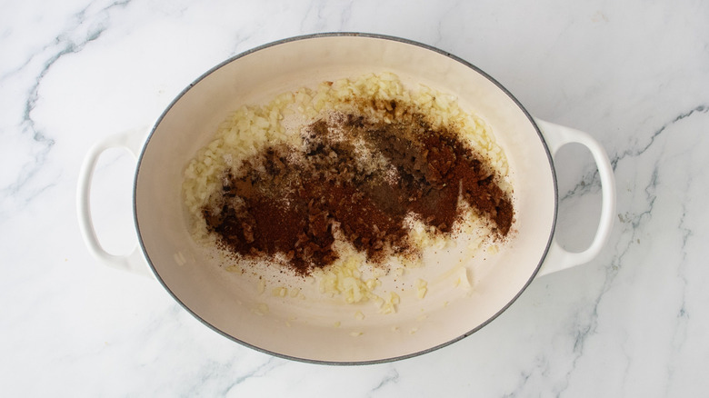 Minced onion and garlic topped with spices in pot