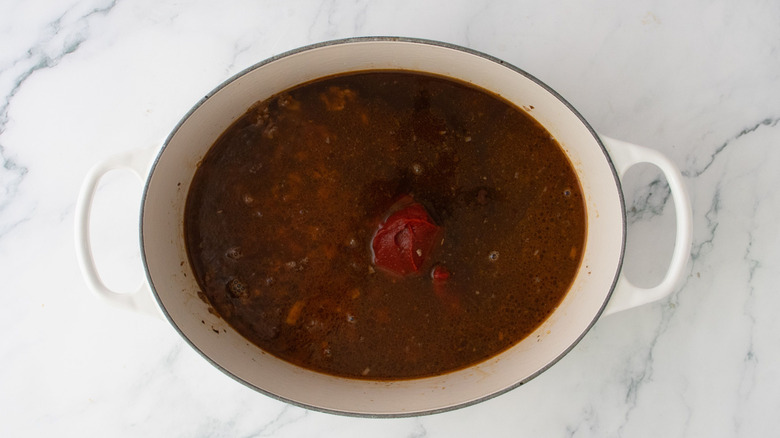 Beef broth mixture with tomato paste in pot