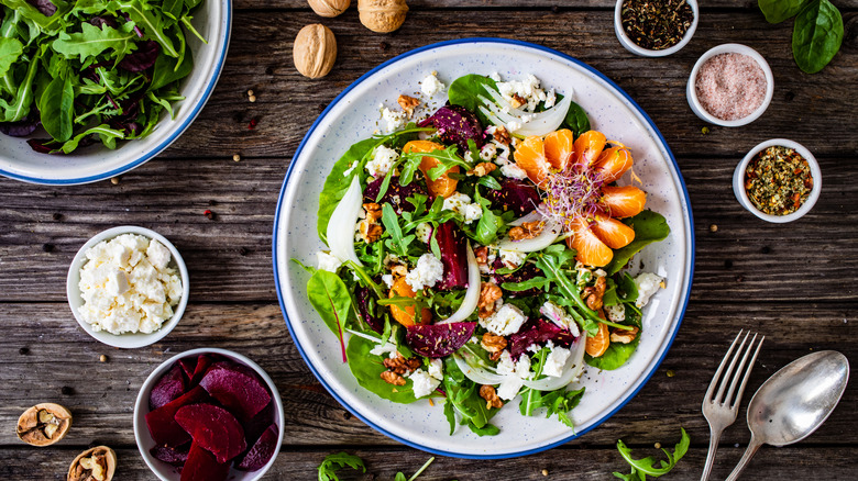 Fancy beet salad on white plate surrounded by ingredients.