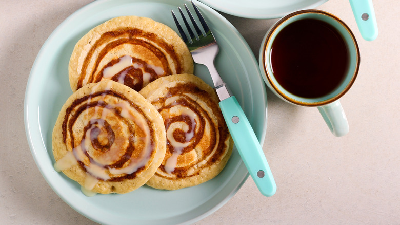 Cinnamon roll pancakes on a plate with a cup of coffee