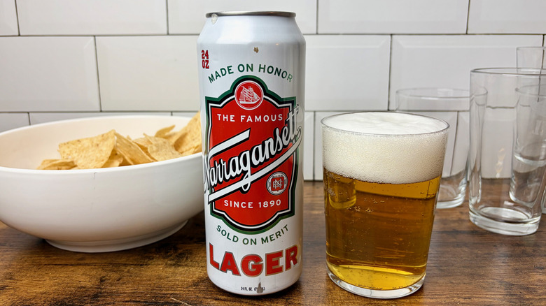 A white and red can of Narragansett Lager beside a full glass of beer