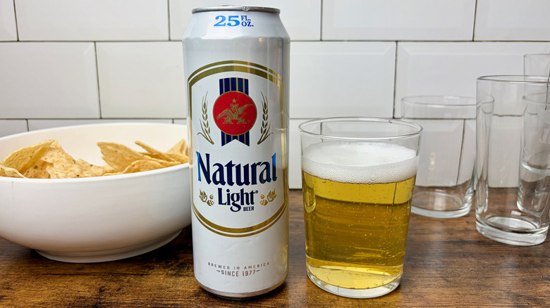 A white can of Natural Light beer beside a glass of beer
