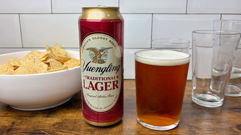 A red can of Yuengling Traditional Lager next to a full glass of beer