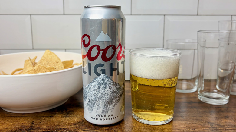 A silver can of Coors Light beside a glass of beer