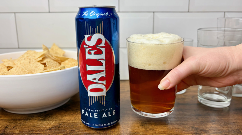 A can of Dale's Pale Ale and a hand holding a full glass of beer