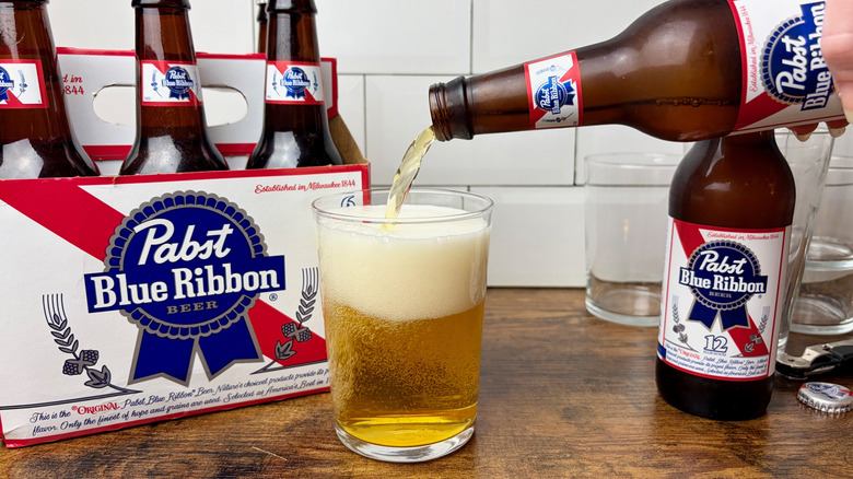A six-pack of Pabst Blue Ribbon Bottles and a glass of beer