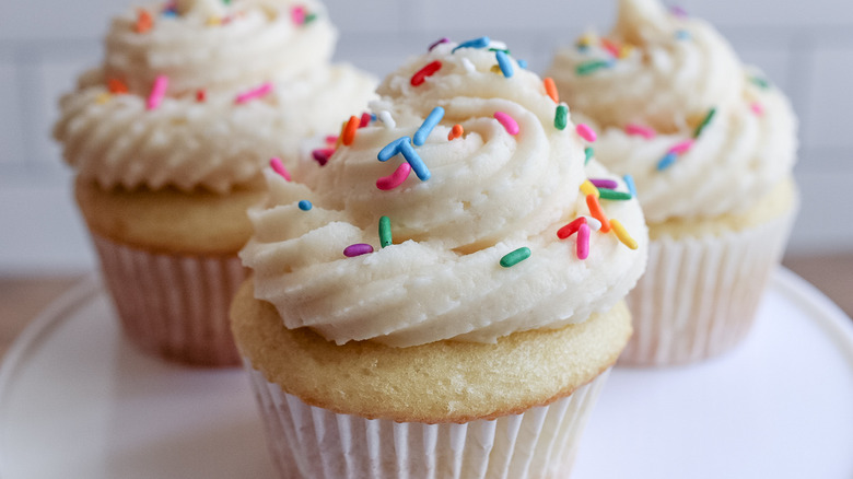 three vanilla cupcakes on plate