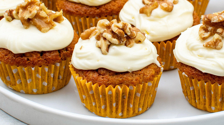 carrot cake cupcakes with cream cheese frosting and walnuts on plate