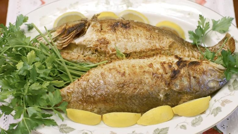 Pair of rice-stuffed fish on platter with lemon slices