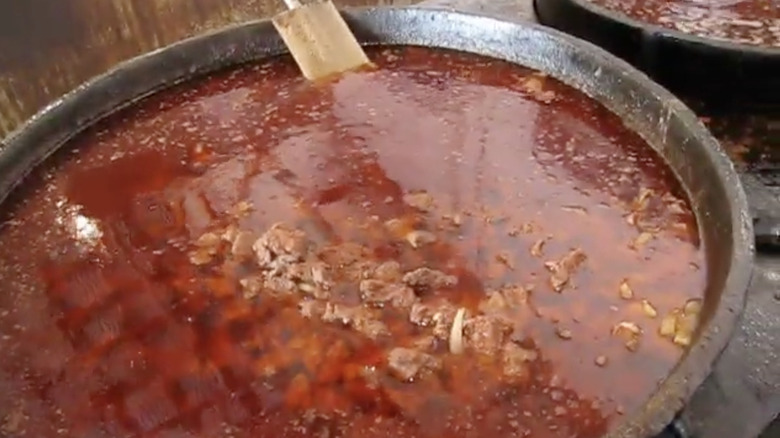 Vats of red broth picnic stew cooking