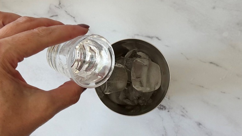 Hand pouring white rum into cocktail shaker