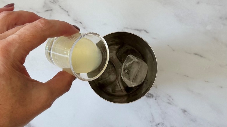 Hand pouring lime juice into cocktail shaker