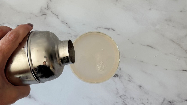 Cocktail pouring from shaker into coupe glass