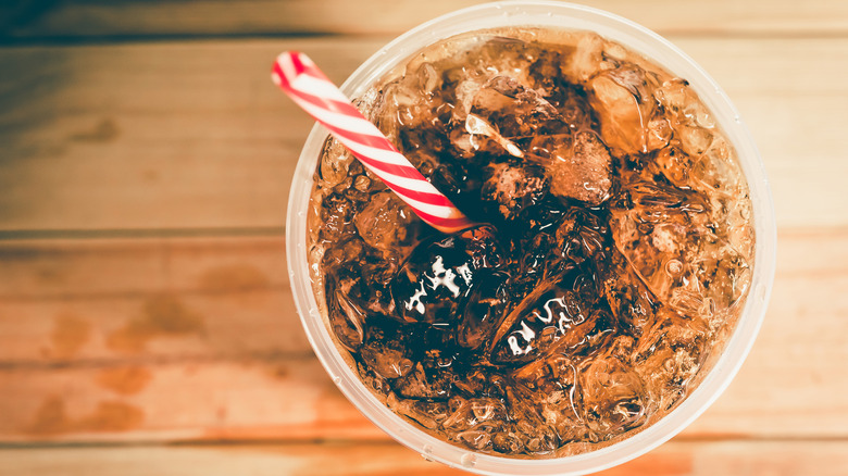 Full cup of soda with red and white straw sitting on a counter