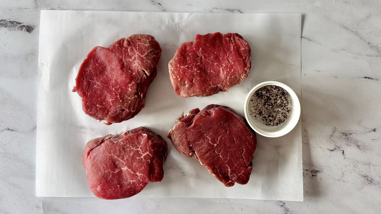 Tenderloin steaks next to bowl of salt and pepper