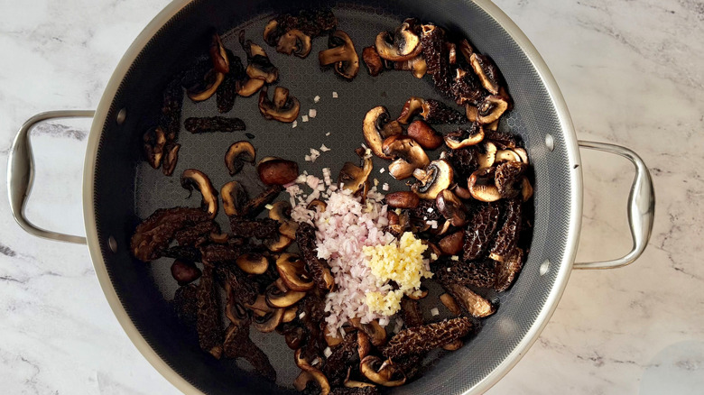 Diced shallot and garlic with sauteed mushrooms in skillet