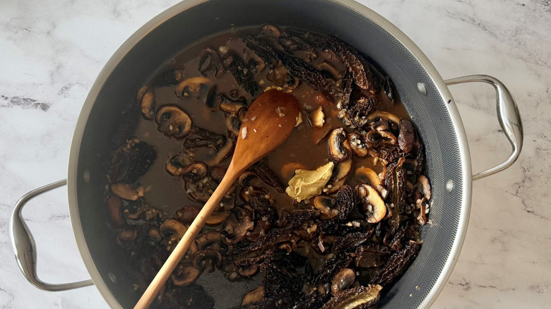 Wooden spoon in skillet with sauteed mushrooms and mustard