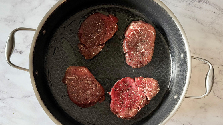 Raw steaks in skillet