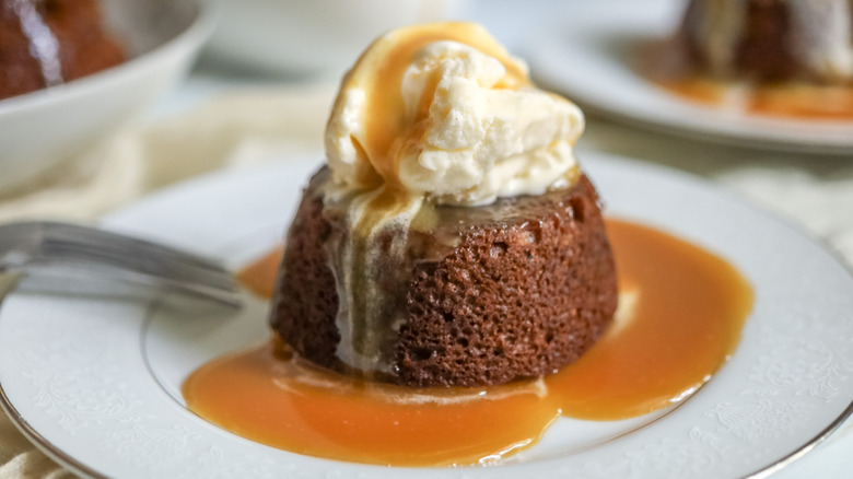 Sticky toffee pudding serving on plate with ice cream and toffee sauce