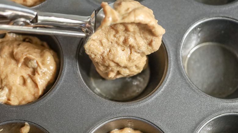 Scooping sticky toffee pudding batter into muffin tin
