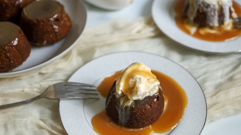 Sticky toffee pudding serving on plate with ice cream and toffee sauce