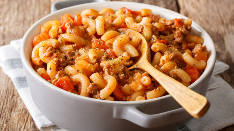 American goulash with wooden spoon in white bowl