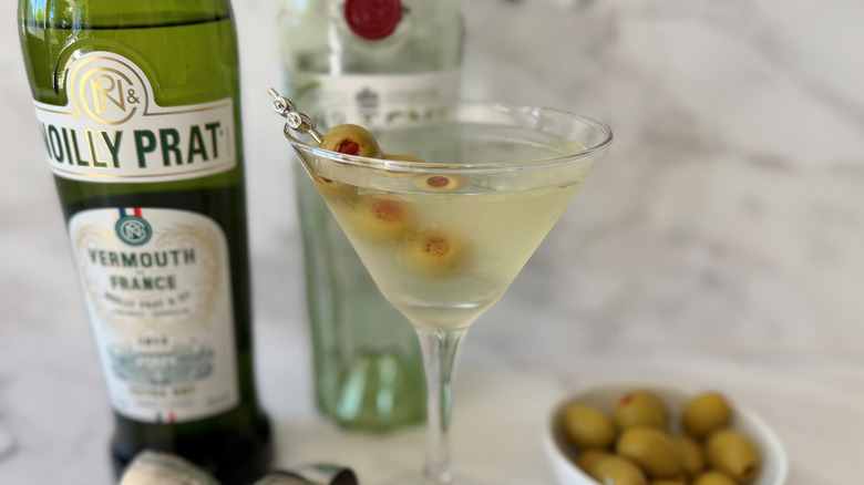 Martini with olives next to liquor bottles