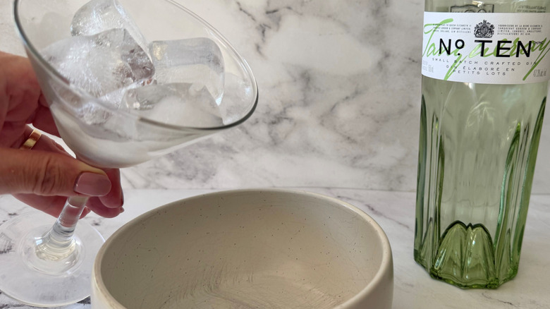 Hand dumping ice out of martini glass into a bowl