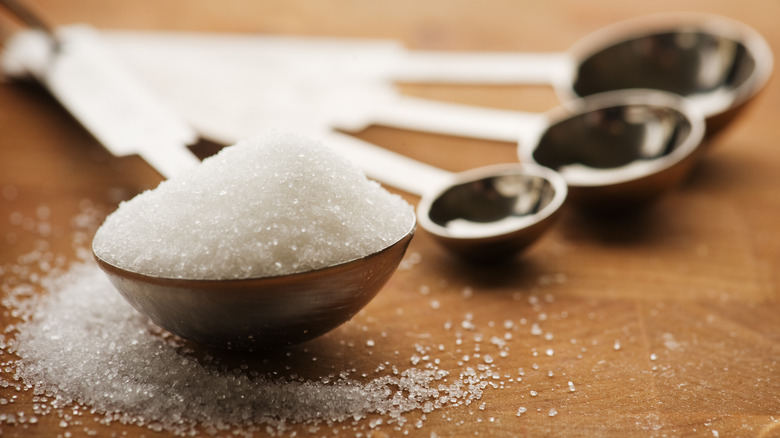 silver measuring spoons with granulated sugar