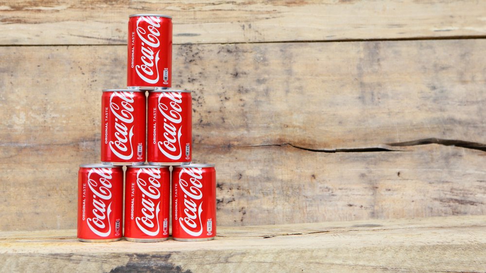 Cans of Coca-Cola stacked on wooden bench