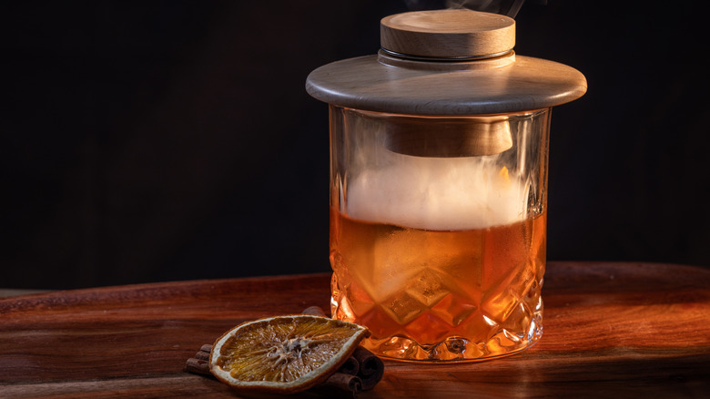 An old fashioned, smoked under a lid on a wooden table
