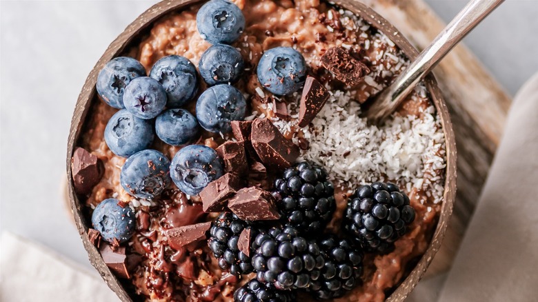 Chocolate oatmeal with coconut, chocolate chunks, blueberries, and blackberries in a bowl