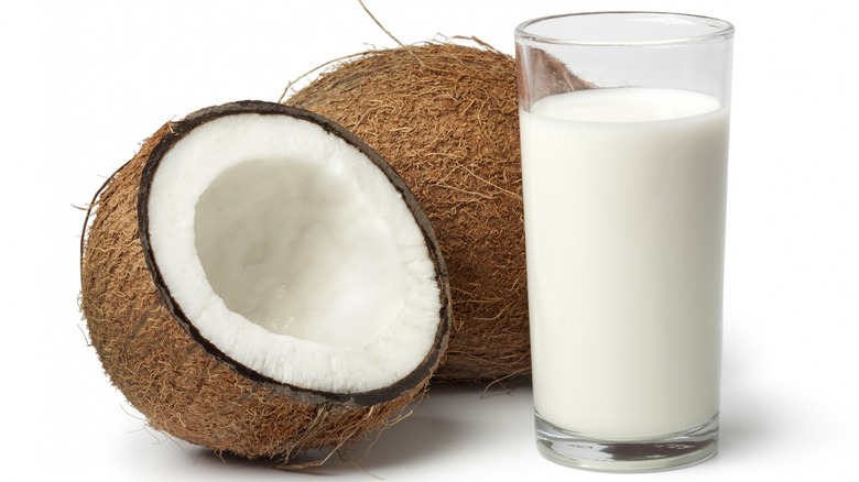 two coconuts sitting next to a glass of coconut milk