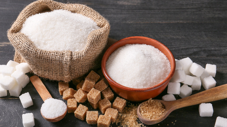 Bowls of sugar and sugar cubes on dark table