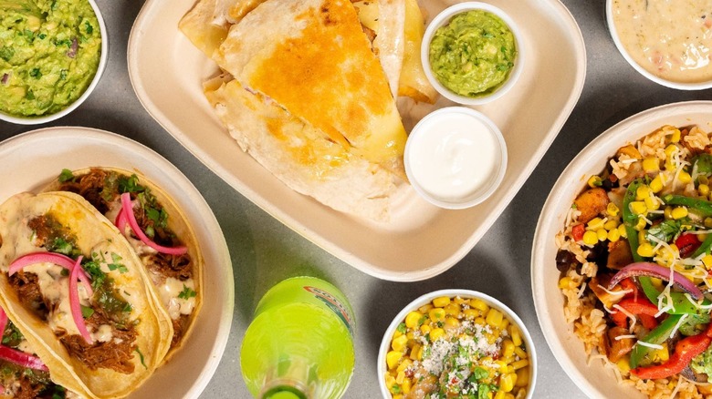 A selection of Qdoba dishes, including a rice bowl, corn, tacos, and quesadilla
