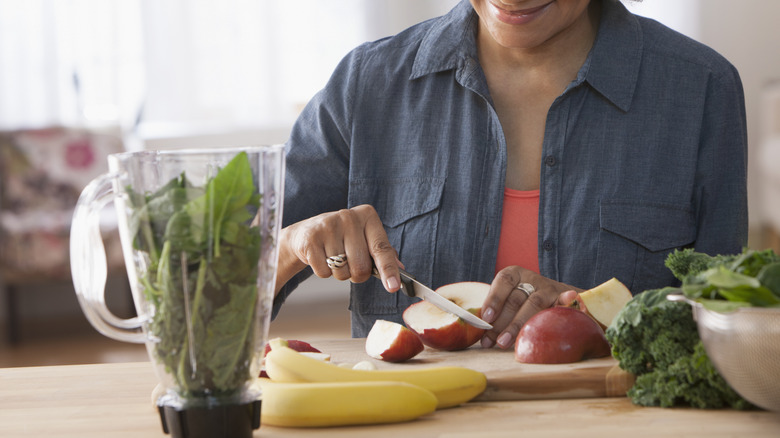 woman making salad with greens and fruit