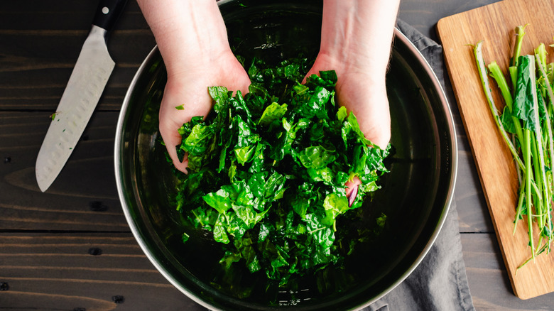 person massages chopped kale