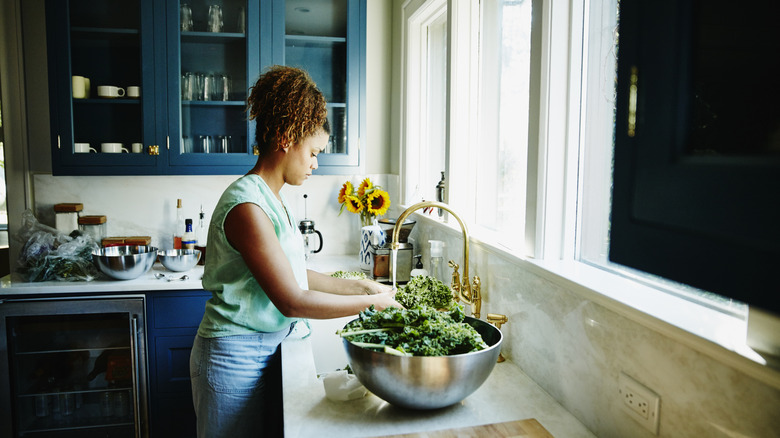 person washing greens at the sink