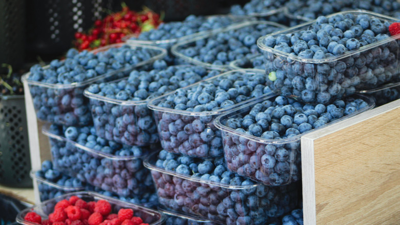 containers of blueberries stacked at a market in a wooden crate