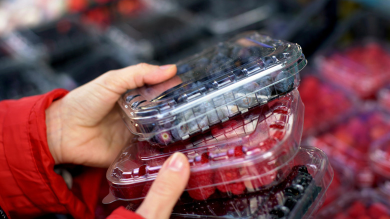 woman holding plastic clamshell containers of berries