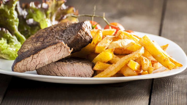 well done steak on plate with French fries